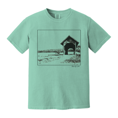 Front view of the Covered Bridge cotton t‑shirt in Seafoam (teal), with a storybook scene of a rustic covered bridge arching over a quiet Vermont dirt road.