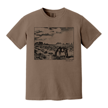 Desert Horse t-shirt in Espresso (brown), with a lone horse grazing before desert buttes under a softly clouded southwestern sky.