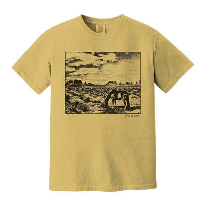 Desert Horse t-shirt in Mustard (yellow), with a lone horse grazing before desert buttes under a softly clouded southwestern sky.