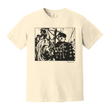 Front view of the Fisherman Cotton T-Shirt in Ivory (cream), featuring a vintage portrait of a fisherman in flannel, gripping ropes on a boat with a cigar in his mouth.